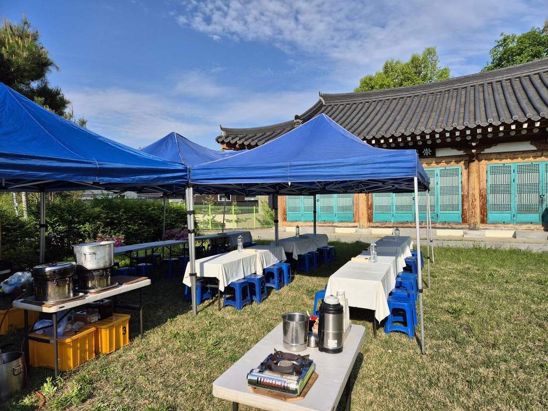 제실 마당에 천막을 치고 긴 테이블을 차린 문중 행사 현장