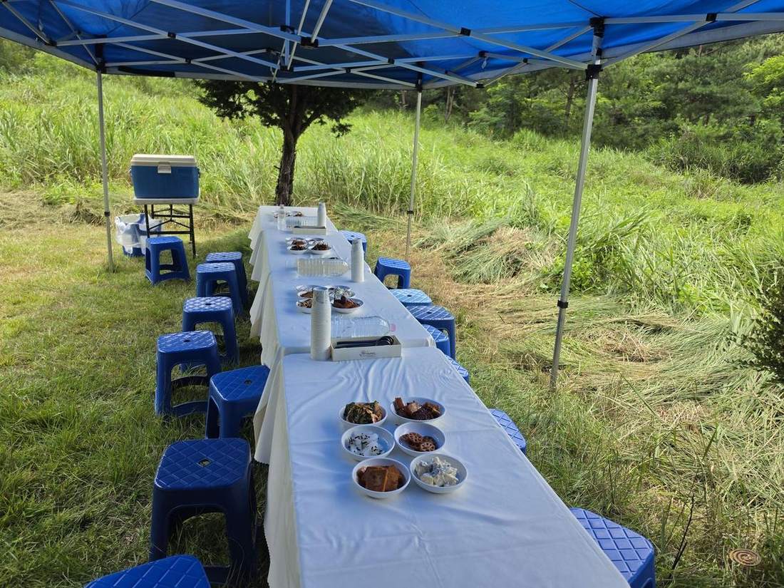 야외 천막 아래 긴 테이블에 음식을 차린 음복상